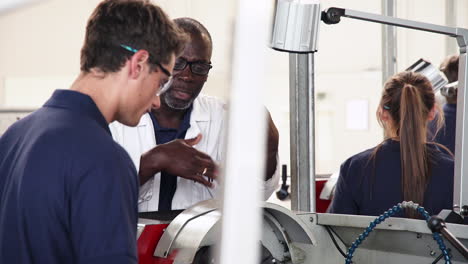 engineer teaching apprentice how to use machine in factory