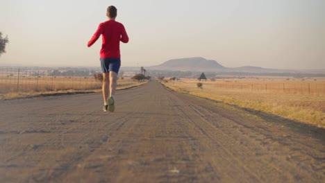 el hombre pasa corriendo por un camino de grava durante el invierno