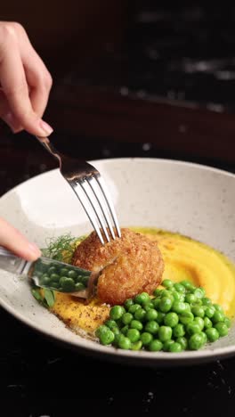 mujer comiendo una deliciosa chuleta con puré de patatas y guisantes