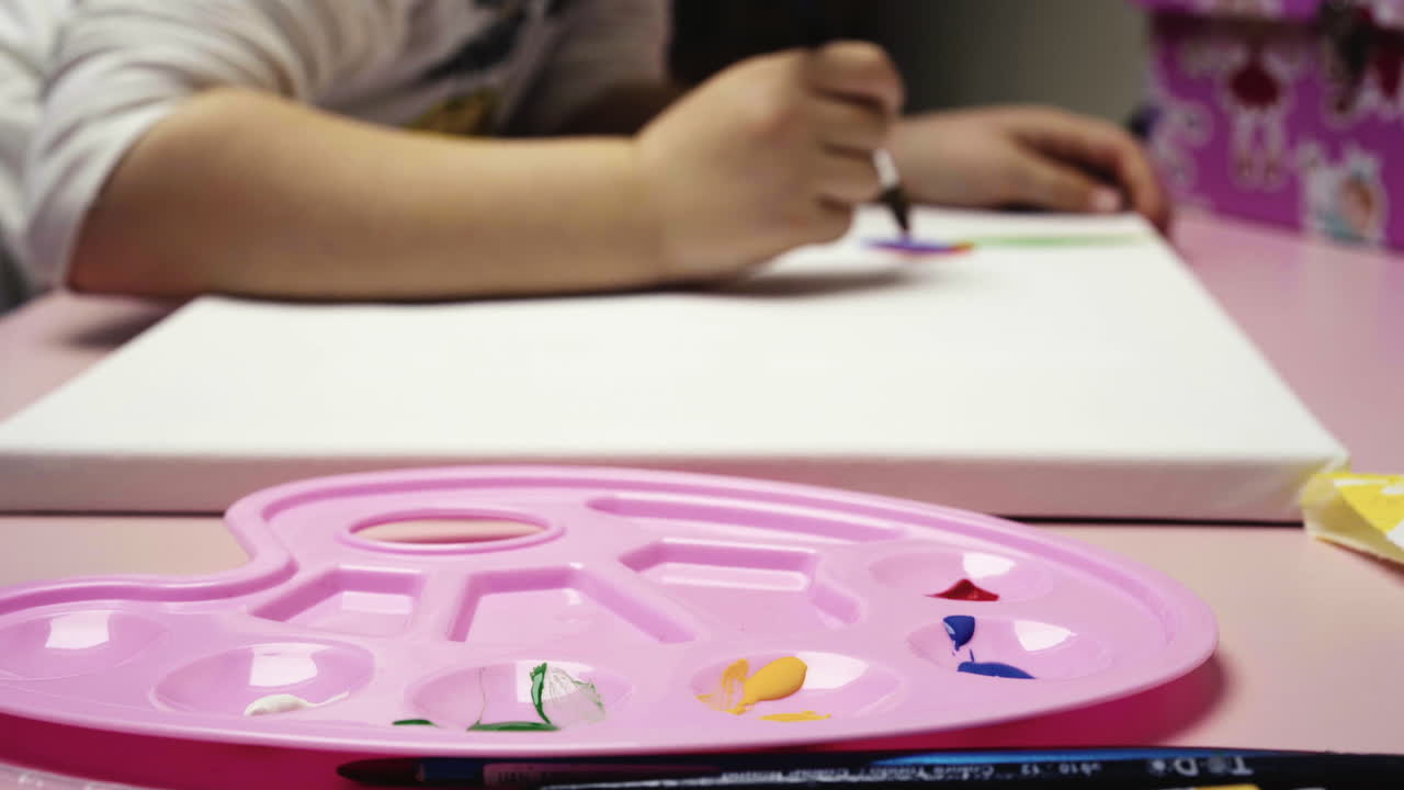 Pembe paletten suluboya ile resim yapan küçük kızın yakın çekimi 4K