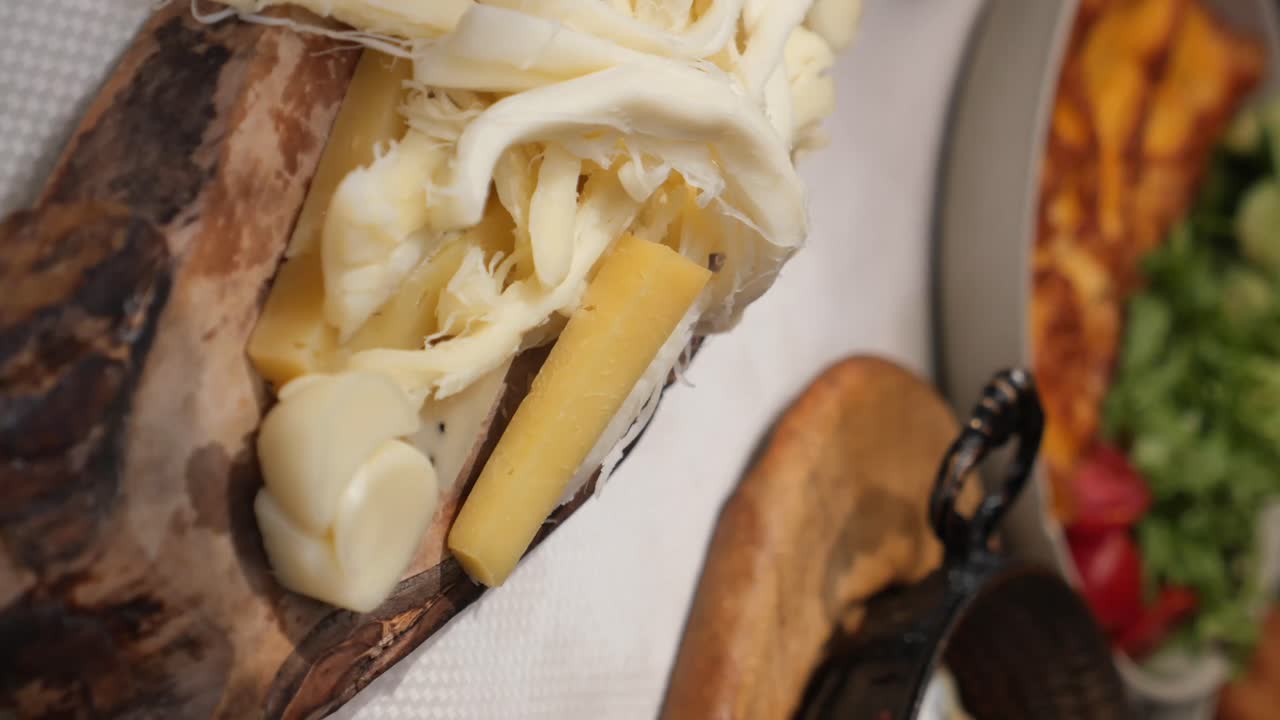Close-up of various cheeses, including string cheese, on a wooden platter