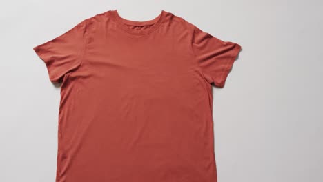 Video-Der-Flachen-Lage-Eines-Orangefarbenen-T-Shirts-Mit-Kopierraum-Auf-Weißem-Hintergrund