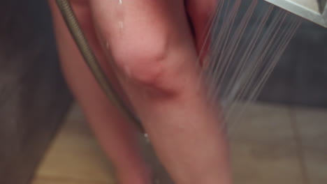 close up of woman washing leg under handheld shower in tiled bath, water streams cascading over skin, capturing refreshing bathing routine and wellness vibe and self care essence