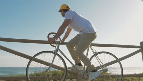 Male-Cyclist-On-A-Boardwalk-Looking-At-The-Sea