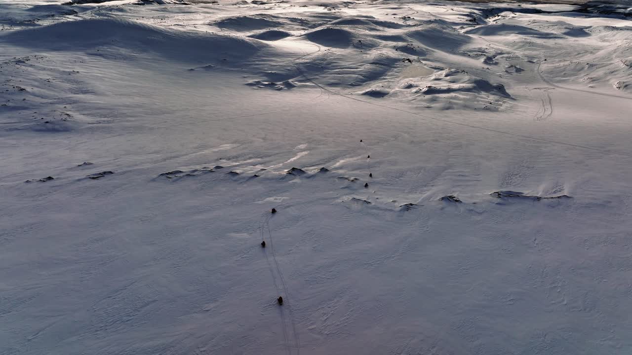 Aerial landscape view over people riding snowmobiles on Myrdalsjokull glacier in Iceland, during an epic sunset