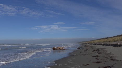 Walking-along-beach-at-high-tide-with-dense-cloud-bank-on-horizon---Pegasus-Bay,-New-Zealand