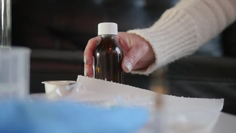 close-up of grabbing a medicine bottle from a table