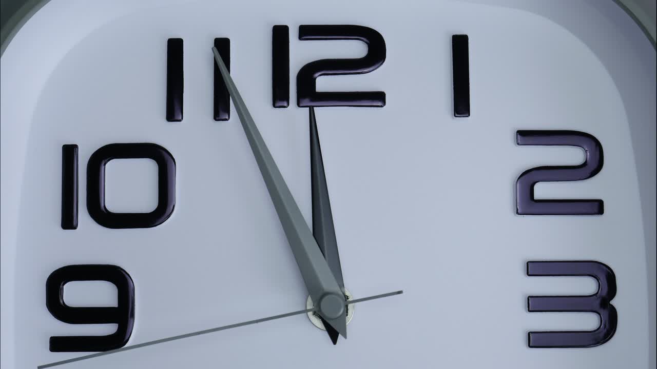Primo piano di un orologio da parete bianco che segna le 12.