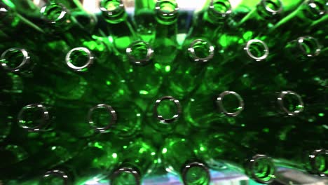 green glass bottles lined up in a bottling factory on conveyor belt