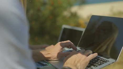 disparo recortado de una pareja usando computadoras portátiles al aire libre