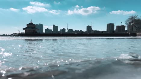 milwaukee skyline in background of water rushing down frozen lake michigan, blue sky