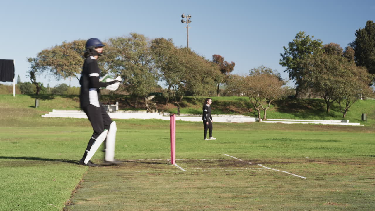 Playing cricket, female wicketkeeper in protective gear standing behind stumps