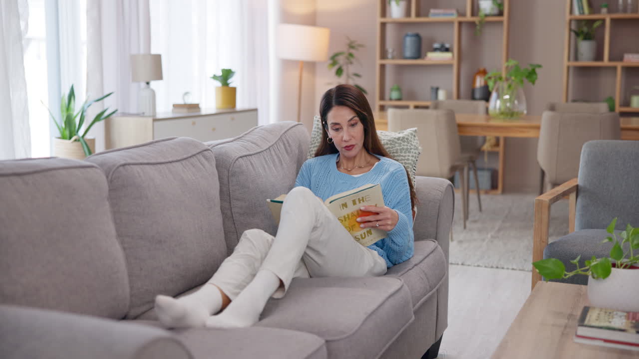 편안한 거실에서 책을 읽으며 소파에서 휴식을 취하는 여자