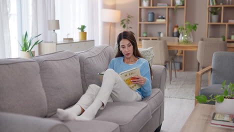 woman relaxing on a couch, reading a book in a cozy living room