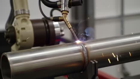 robotic welding process: close-up of automated welding torch joining metal pipes with precision and producing bright sparks and glow