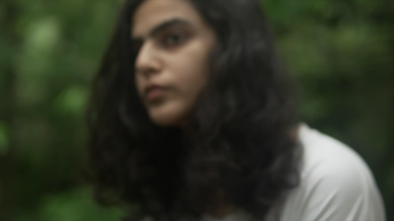 el primer plano muestra el rostro de una joven india con una expresión triste, mientras contempla la destrucción del planeta.