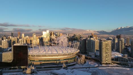 aerial view of vancouver commercial buildings around the bc place stadium with snow capped mountains in the background