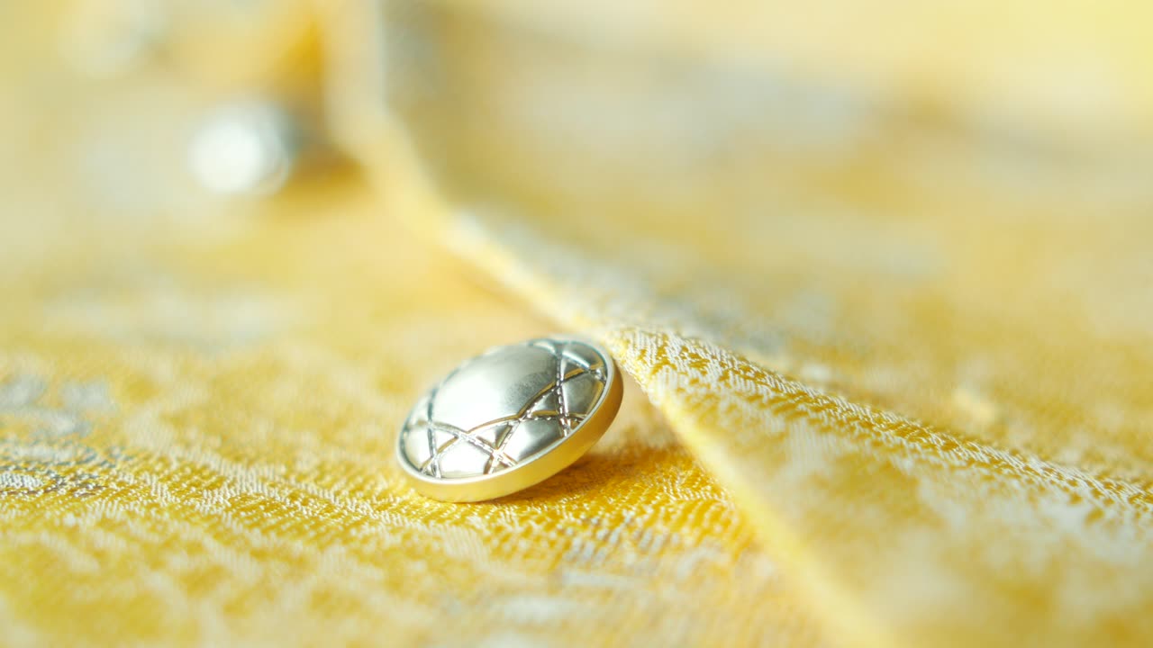 Close-up of a silver button on a yellow fabric