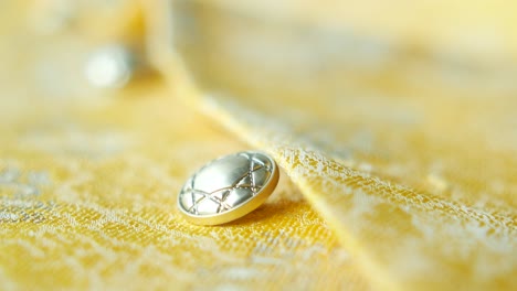 close-up of a silver button on a yellow fabric