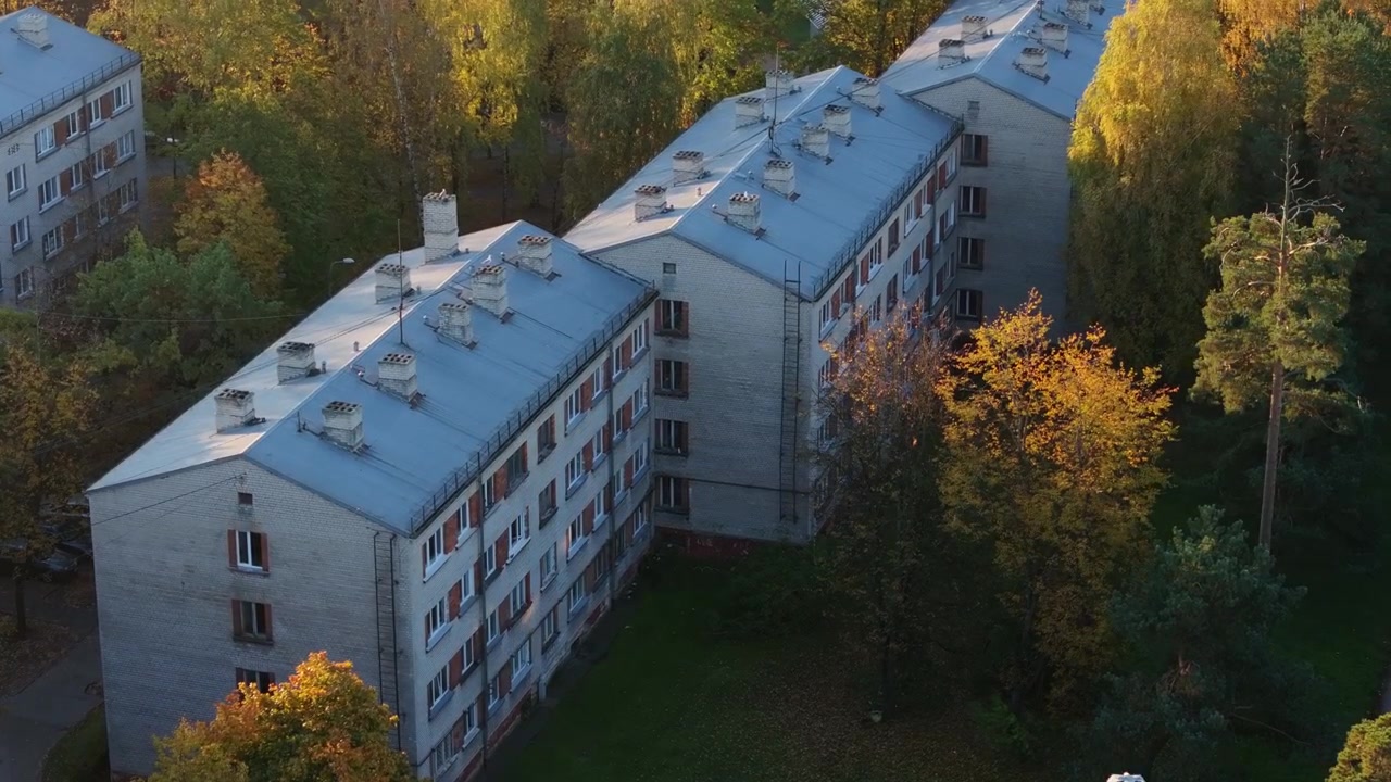 Khrushchyovka building at autumn sunrise with a seagull flying into the frame.