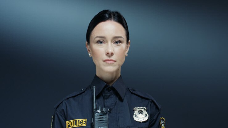 Ritratto di una bella poliziotta con espressione seria e in uniforme che guarda dritto verso la telecamera