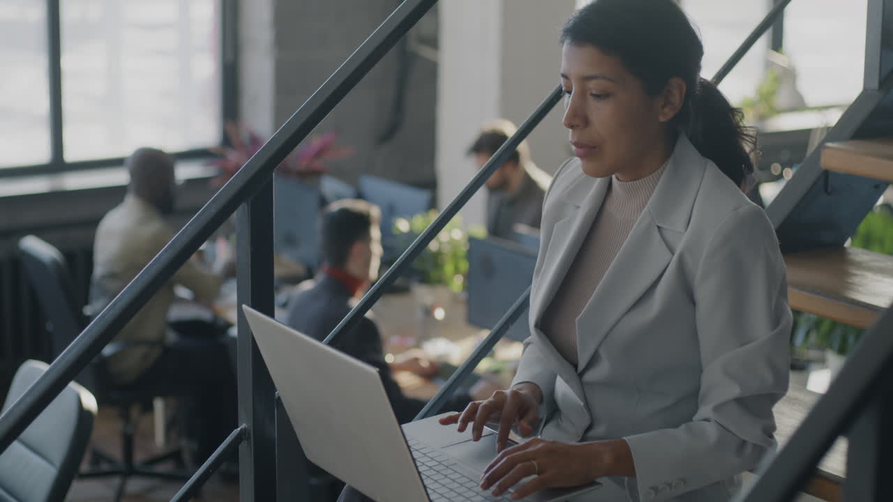 Business Woman Working on Laptop on Stairs in Modern Office
