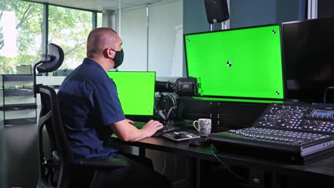 caucasian man working in video edit suite with multiple screens, chroma key