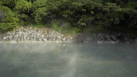 fog or steam is lying on top of a still water lake. camera is zooming out while fog blows to the right