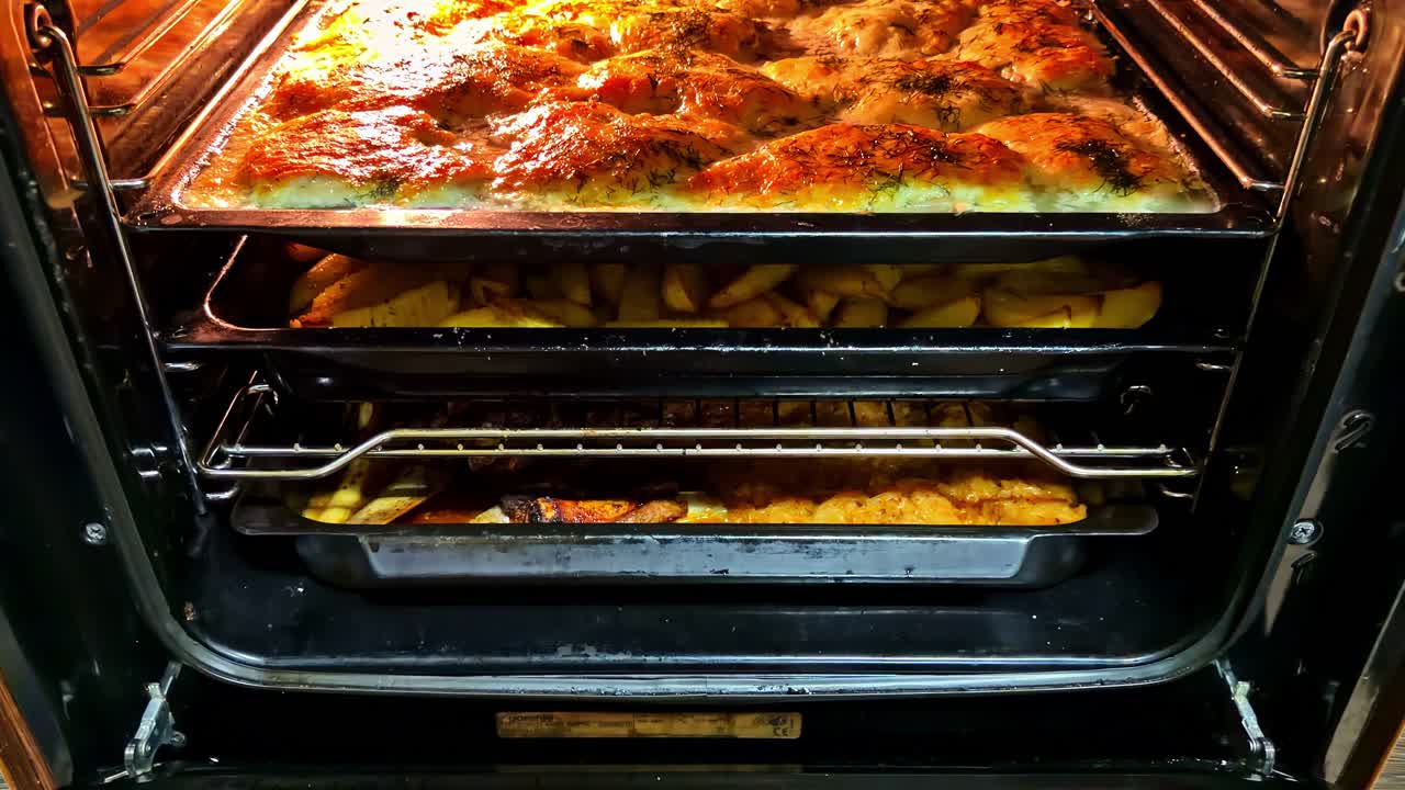 Sprød, bagt ret i moderne køkkenovn med gylden topping og bakker med mad