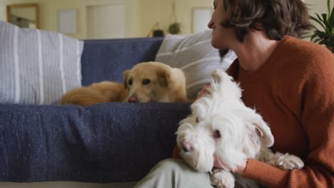 Caucasian-woman-kissing-and-cuddling-her-pet-dogs-sitting-on-sofa-at-home