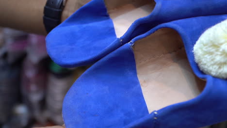 Stylish-navy-blue-Belgha-leather-shoes-showcasing-Moroccan-craftsmanship-in-the-vibrant-old-medina-market-of-Marrakech