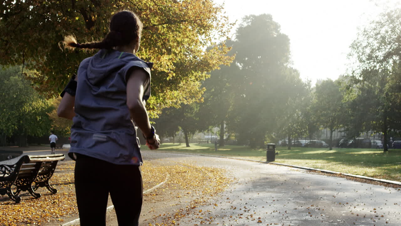 Runner woman running in park exercising outdoors fitness tracker wearable technology
