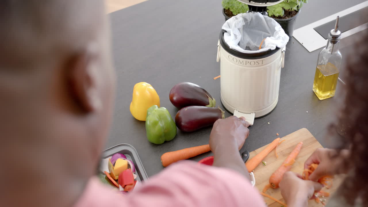 Preparing fresh vegetables in kitchen, couple composting vegetable scraps