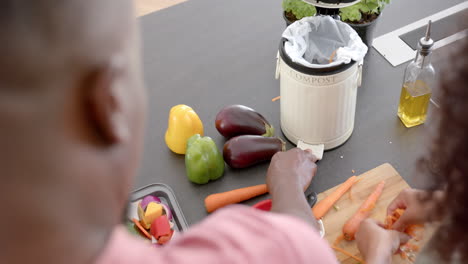 preparing fresh vegetables in kitchen, couple composting vegetable scraps