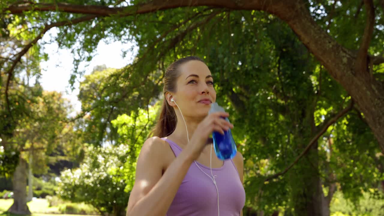 corredor tomando un descanso para beber agua en el parque