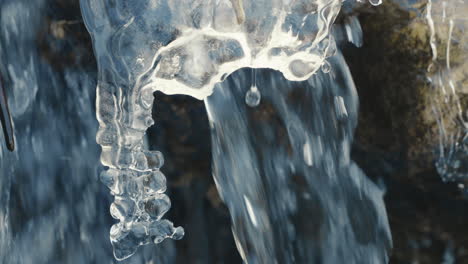 icicle in a frozen river with flowing water in background, close up, slow motion