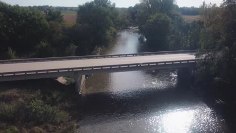 punto de vista vuelo lento de drones de vuelo de baja altitud sobre un puente que cruza el río zorrillo río que atraviesa las zonas rurales de iowa, ee.uu.