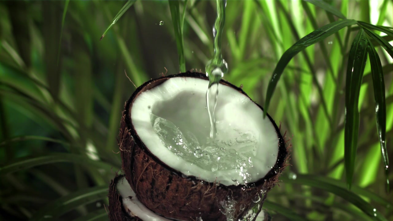 Slow Motion Water Pouring into a Fresh Coconut Half