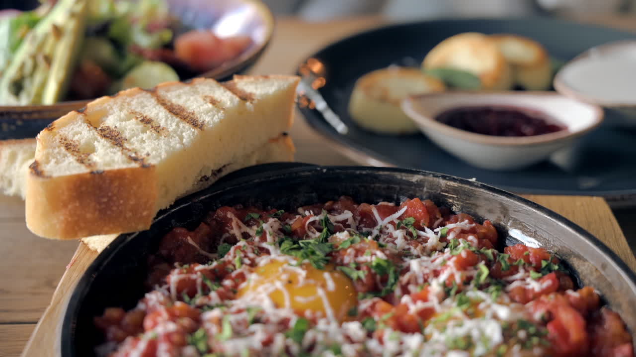 Primo piano di un piatto di shakshouka con due pezzi di pane su un tavolo in un ristorante