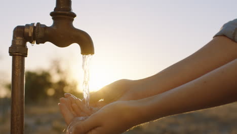 Manos-De-Mujer-Atrapando-Agua-Bajo-El-Grifo-Granjero-Sediento-Bebiendo-Agua-Dulce-Que-Fluye-Del-Grifo-Al-Atardecer-Concepto-De-Ahorro-De-Agua