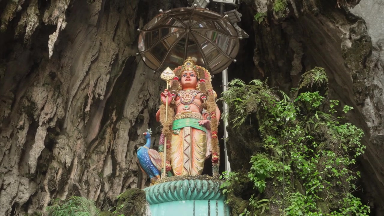 Ripresa fluida con gimbal in orbita che circonda una statua di divinità indù all'ingresso delle Grotte di Batu, circondata da formazioni calcaree