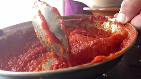 movimiento lento agitando salsa de tomate para espagueti o pizza en la cocina de cerca