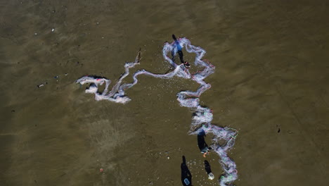 Local-fisherman-shaking-fish-catch-out-of-white-nets-on-beach