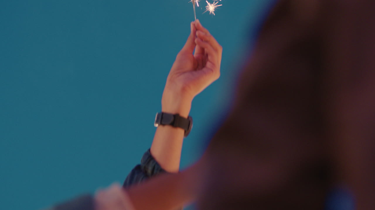 밤에 새해 전야 휴일을 축하하는 폭죽을 들고 있는 손