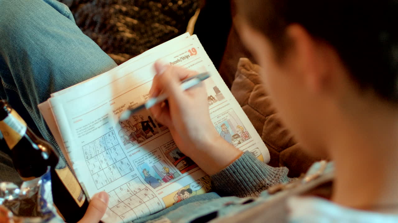 옆면에 맥주와 칩 한 봉지가 있는 신문에서 스도쿠 만들기