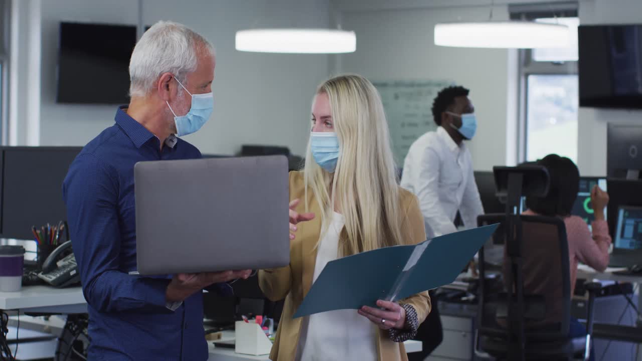 мужчина и женщина в масках обсуждают в офисе.