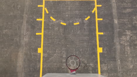 Ascend-Aerial-top-down-shot-of-empty-basketball-court-with-hoop-on-university