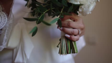 close up of bride's hand holding bouquet with engagement ring in soft light