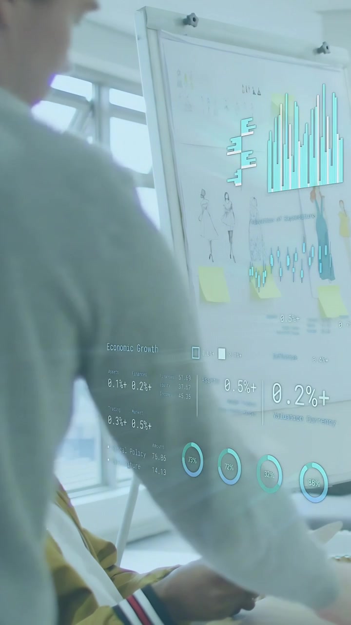 Vertikal video: Mann i genser lener seg mot et diagram, en kollega tapper på telefonen og skaper AR-diagrammer for forretningsbruk.