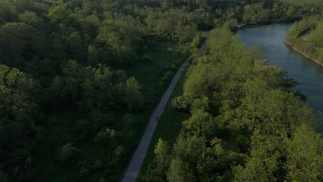 Drone-shot-tracking-cyclist-on-trail-beside-12-mile-creek-in-St